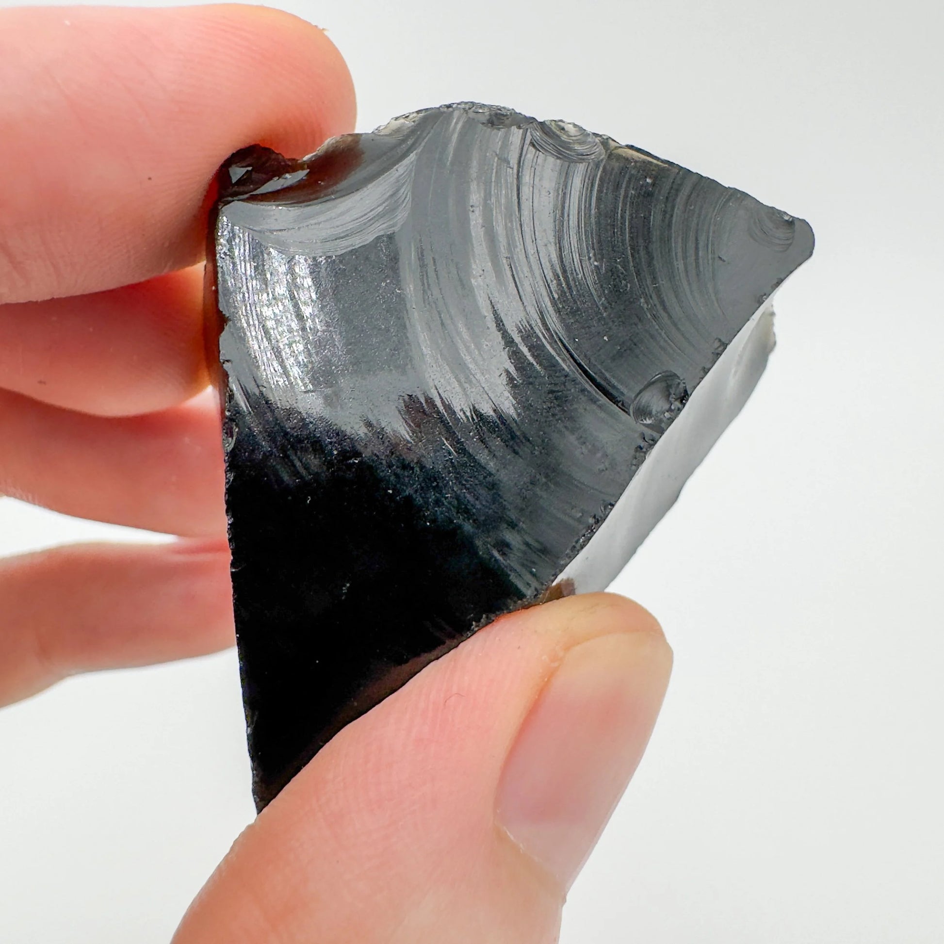 Palm-scale view of a single Black Obsidian raw stone sourced from Argentina.