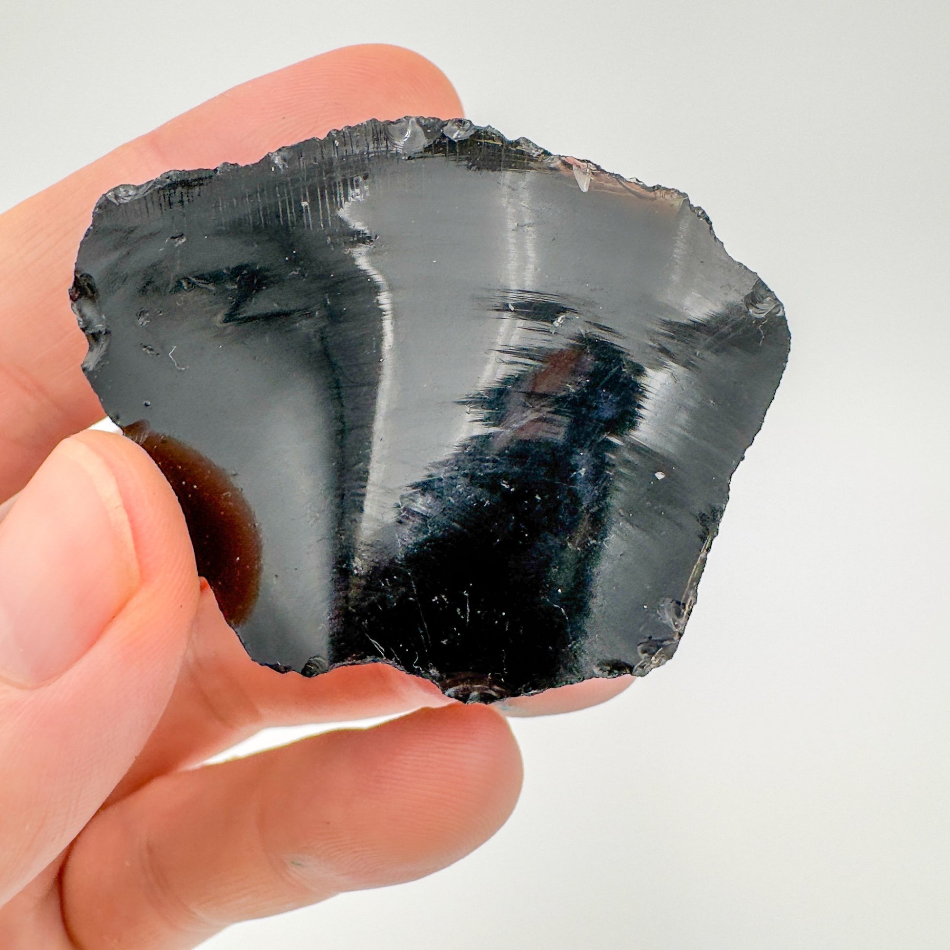 Grade aa black obsidian raw held in hand for size reference