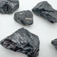 Grade a black tourmaline raw held in hand for size reference