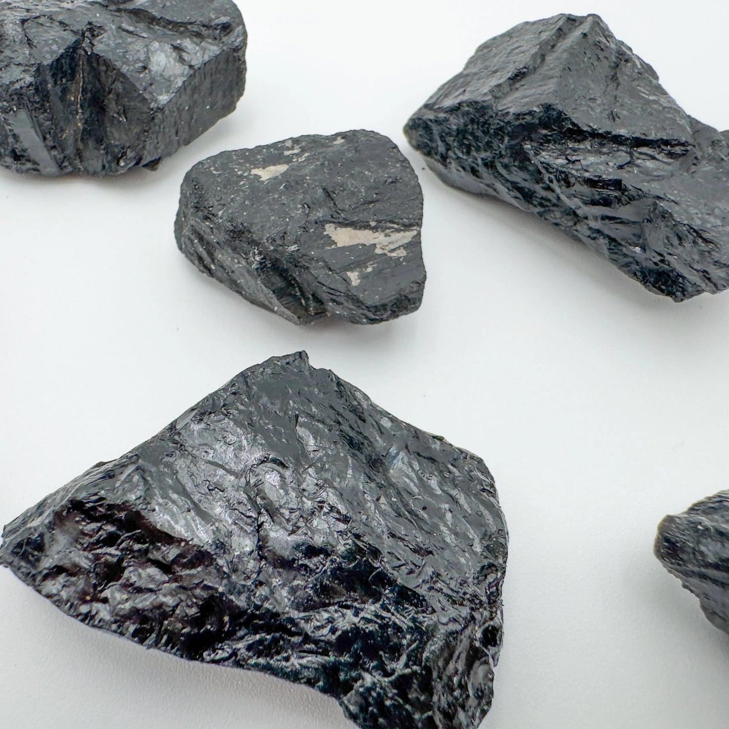 Grade a black tourmaline raw held in hand for size reference