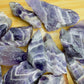Held in hand, a single Chevron Amethyst raw stone sourced from Zambia.