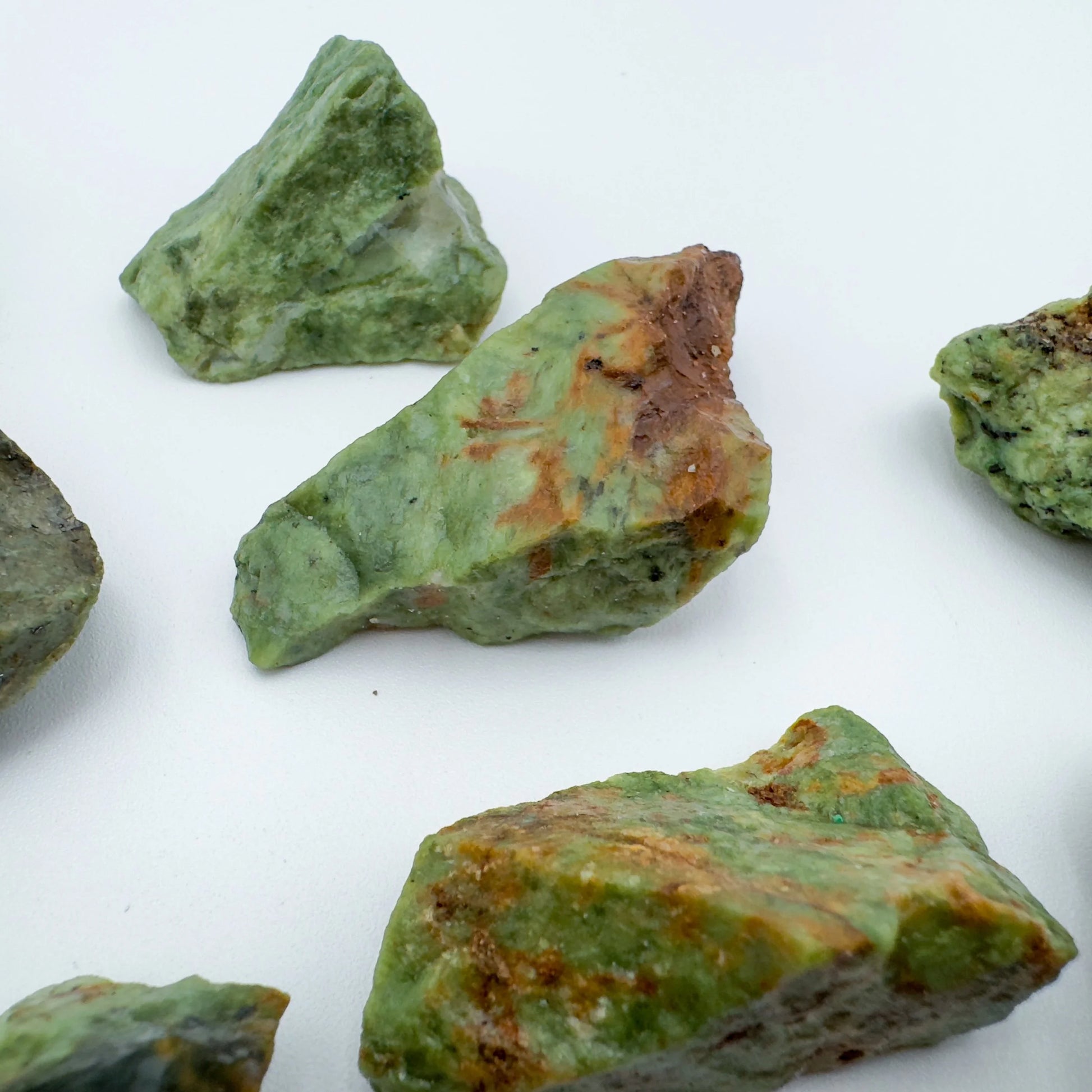 On a soft surface rests a Chrysoprase raw crystal, captured against a quiet backdrop.