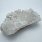 Natural light view of a Clear Quartz specimen held against natural backdrop, sourced from Brazil.