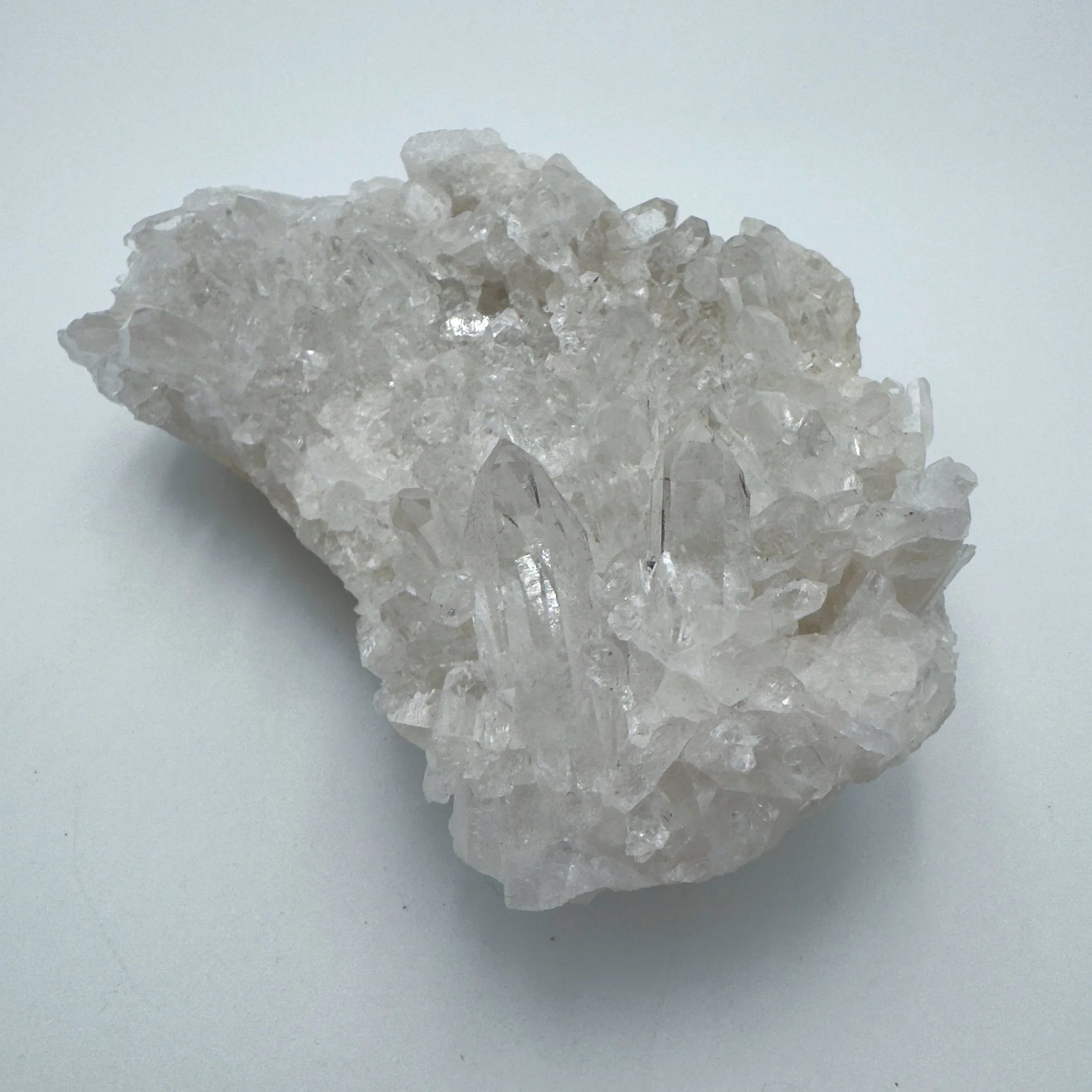 Holding a Clear Quartz specimen, from Rio Grande do Sul, Brazil, set against a soft neutral surface.