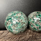 Back view of Grade AA Emerald sphere showing natural surface