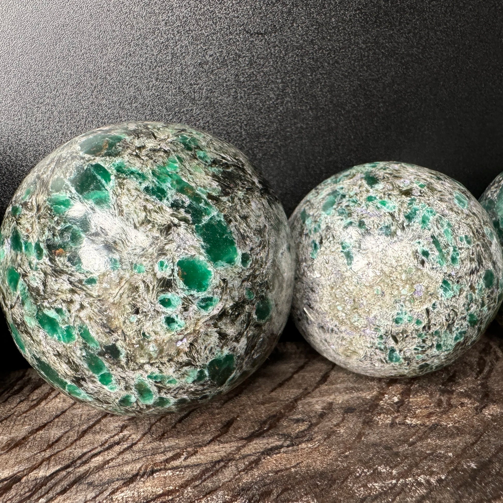 Held against neutral backdrop is an Emerald stone, from Midlands Province, Zimbabwe, linked to Love, captured in natural daylight.