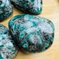 Daylight view of a Emerald palm stone held against natural backdrop.