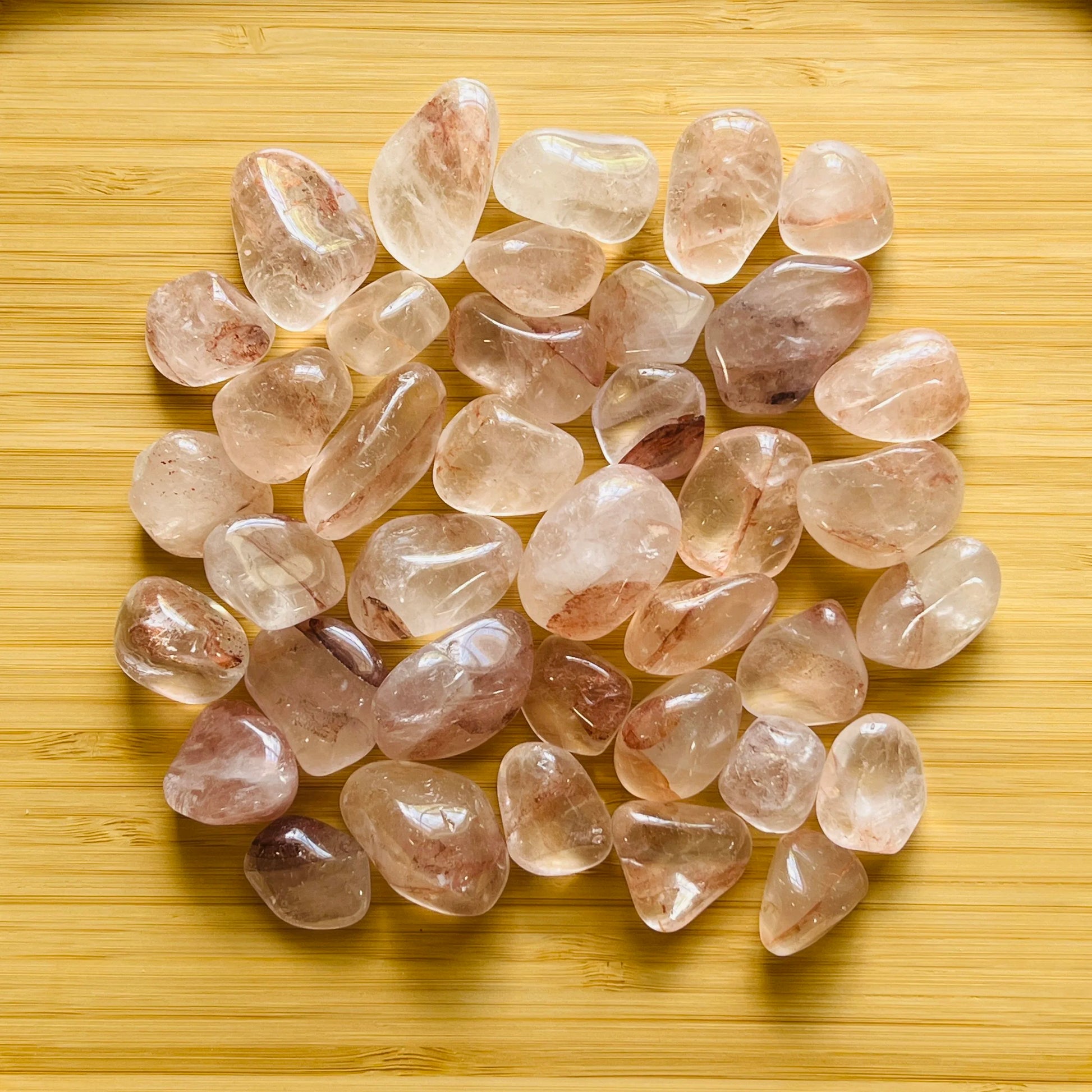 Resting display of Fire Quartz tumbled stone, from Alaotra-Mangoro, Madagascar, shown for shape and scale.