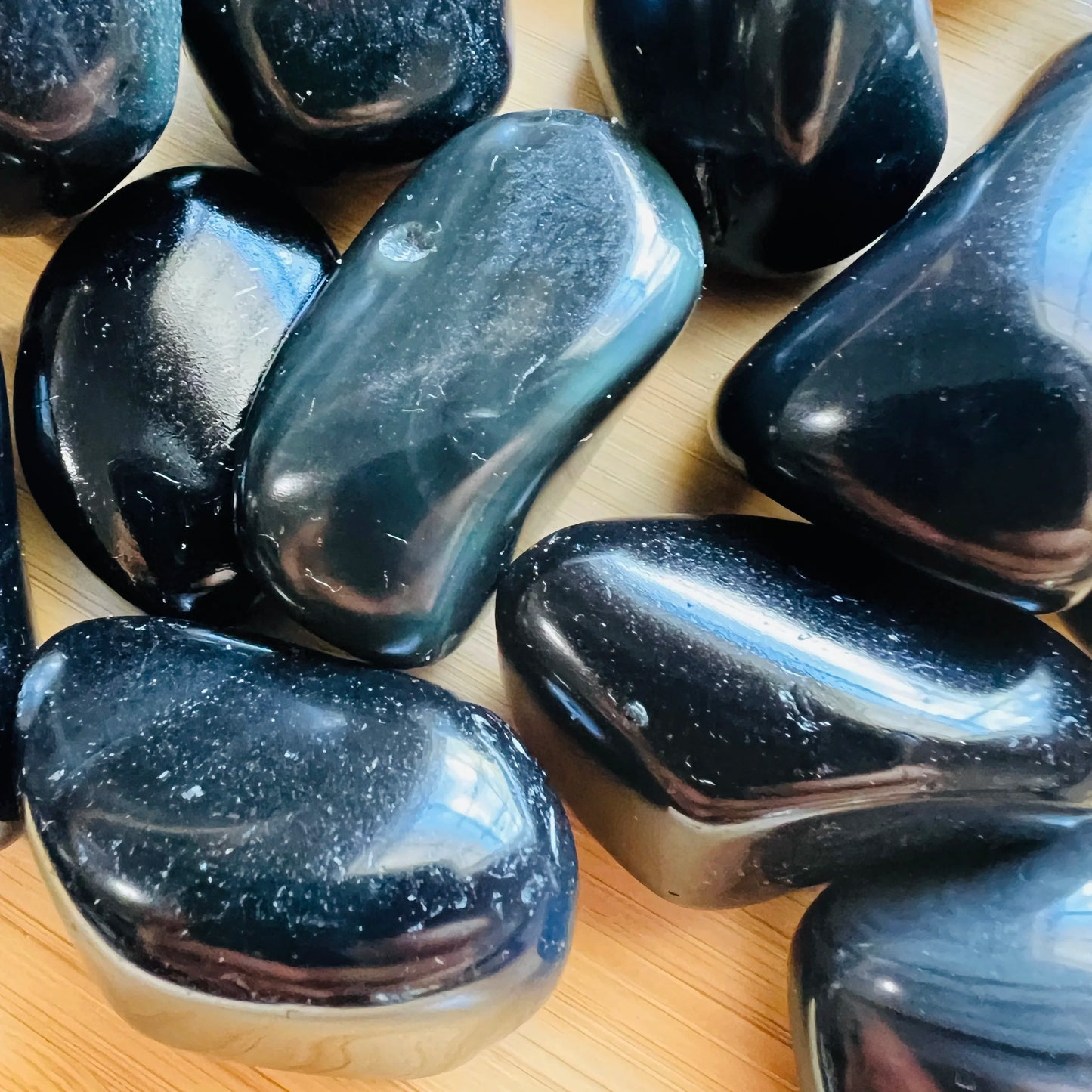 Detail shot of Grade AA Rainbow Obsidian tumbled stone under natural light