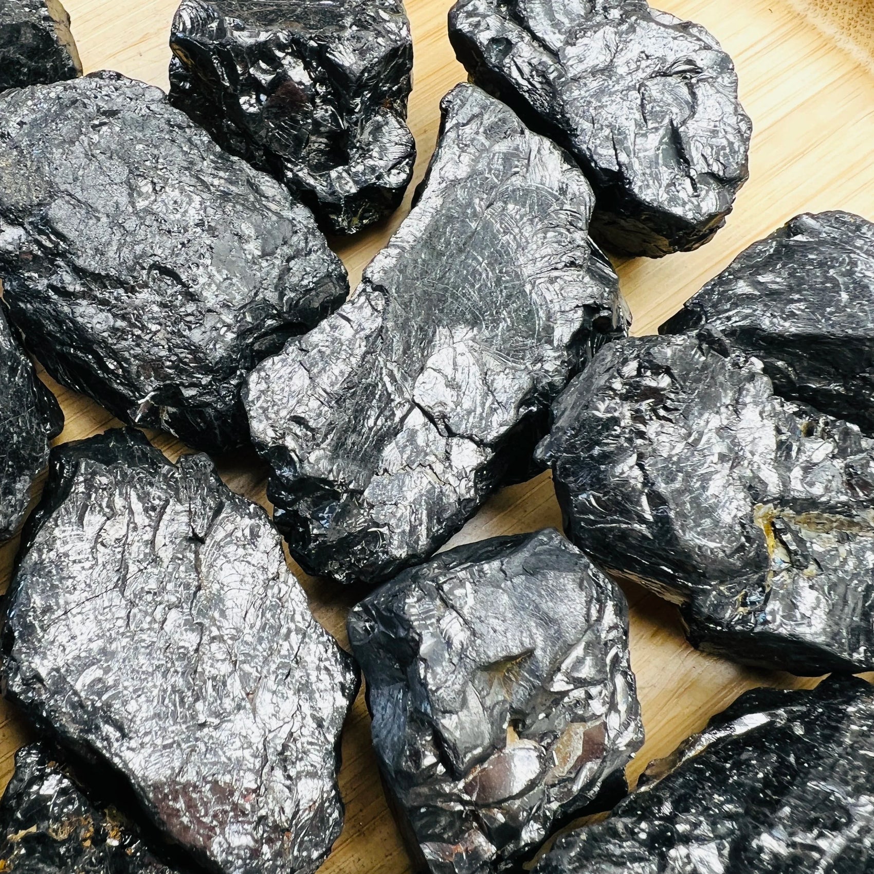 Held in hand, a Shungite raw stone held against natural backdrop, from Russia.