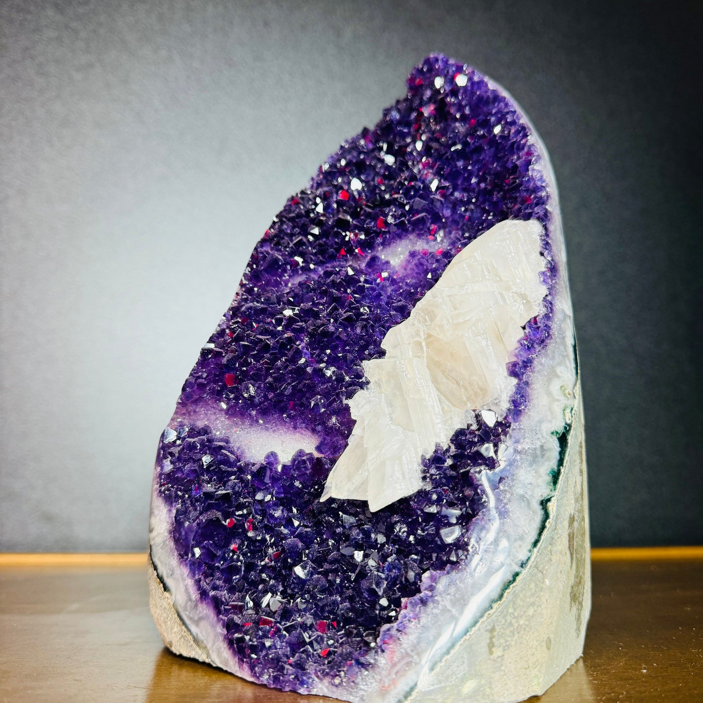 Palm-scale view of a Amethyst raw geode held against natural backdrop.