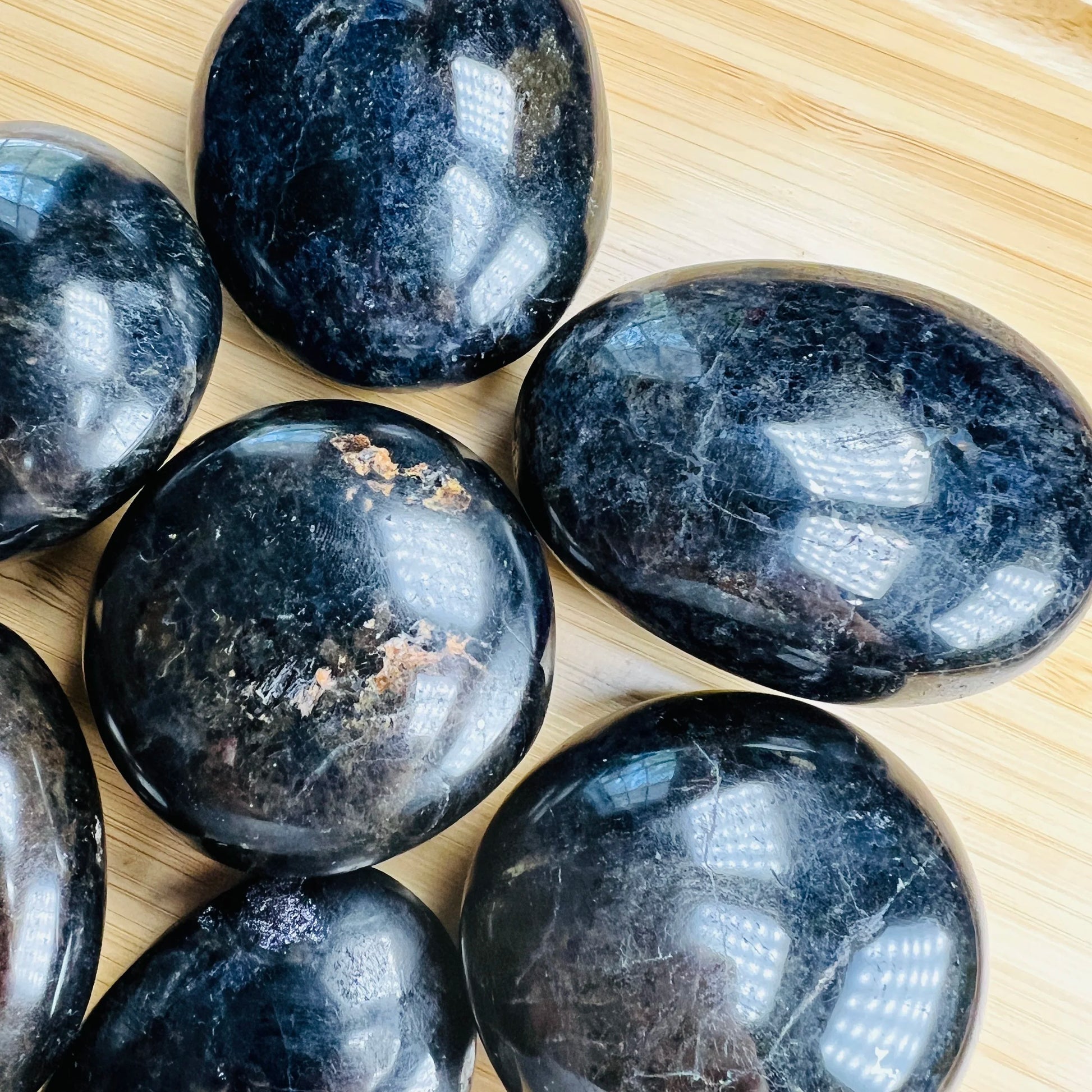 Palm-scale view of a Iolite palm stone held against natural backdrop.