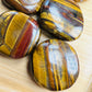 Plan view of Grade AA Tiger Eye palm stone, showing natural inclusions, South Africa-sourced.