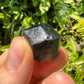 Grade a black tourmaline raw held in hand for size reference