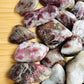 Edge view of Pink Tourmaline tumbled stone, showing natural inclusions.