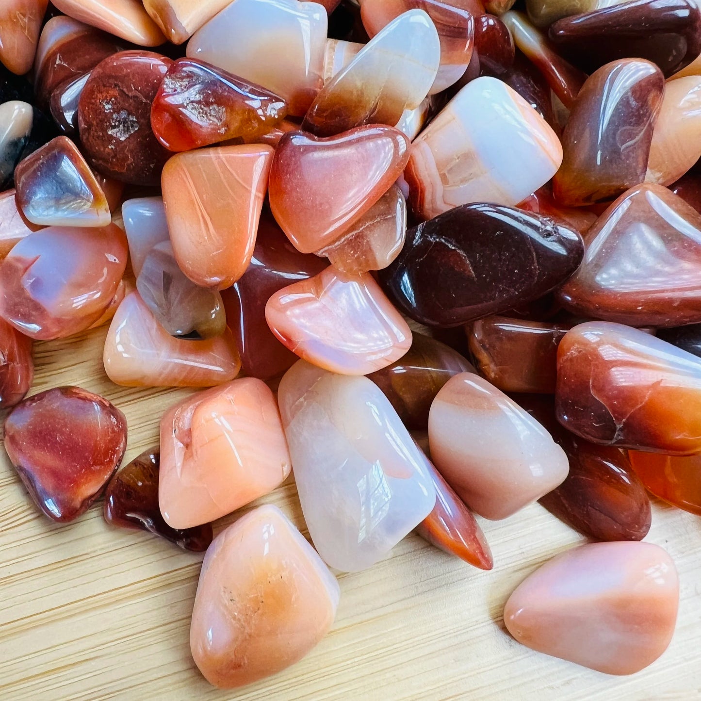 Close-up detail of Grade AA Carnelian tumbled stone showing natural orange, red tones and texture