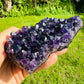 Size comparison with a Amethyst specimen held against natural backdrop, from Uruguay.