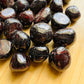 Overhead view of Garnet tumbled stone, showing translucent edges, from Nsipe, Malawi.