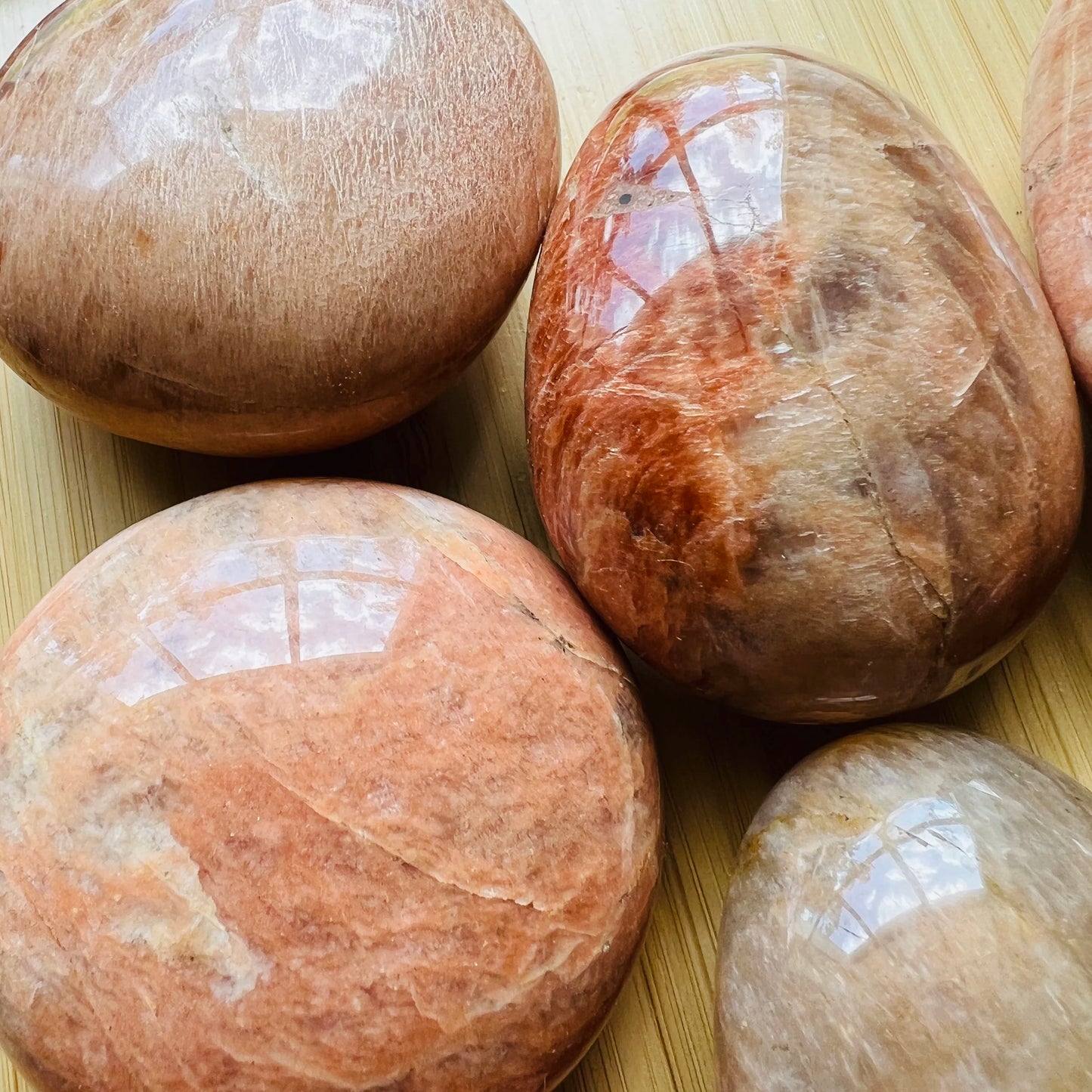 Profile view of Peach Moonstone palm stone, showing translucent edges, turned to for Emotional Healing.