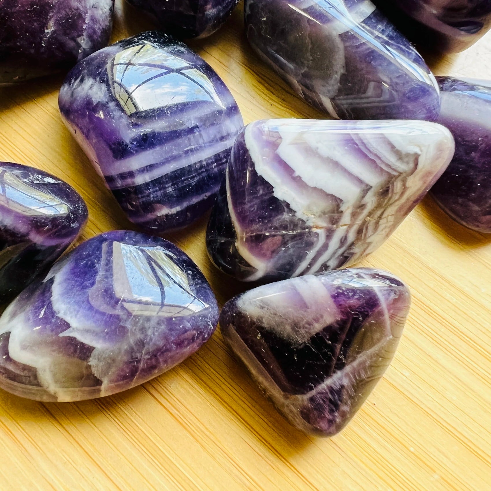 Overhead angle of purple Chevron Amethyst tumbled stone, showing soft luster, worked with for Intuition.