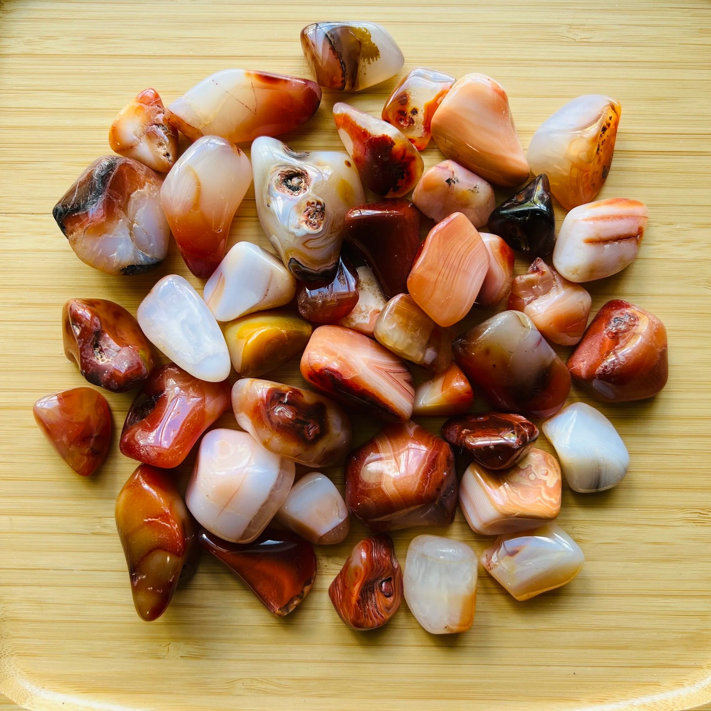 Close-up detail of Grade AA Carnelian tumbled stone showing natural orange, red tones and texture