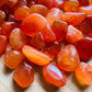 Overhead angle of Grade AA Carnelian tumbled stone, showing characteristic color, associated with Energy.