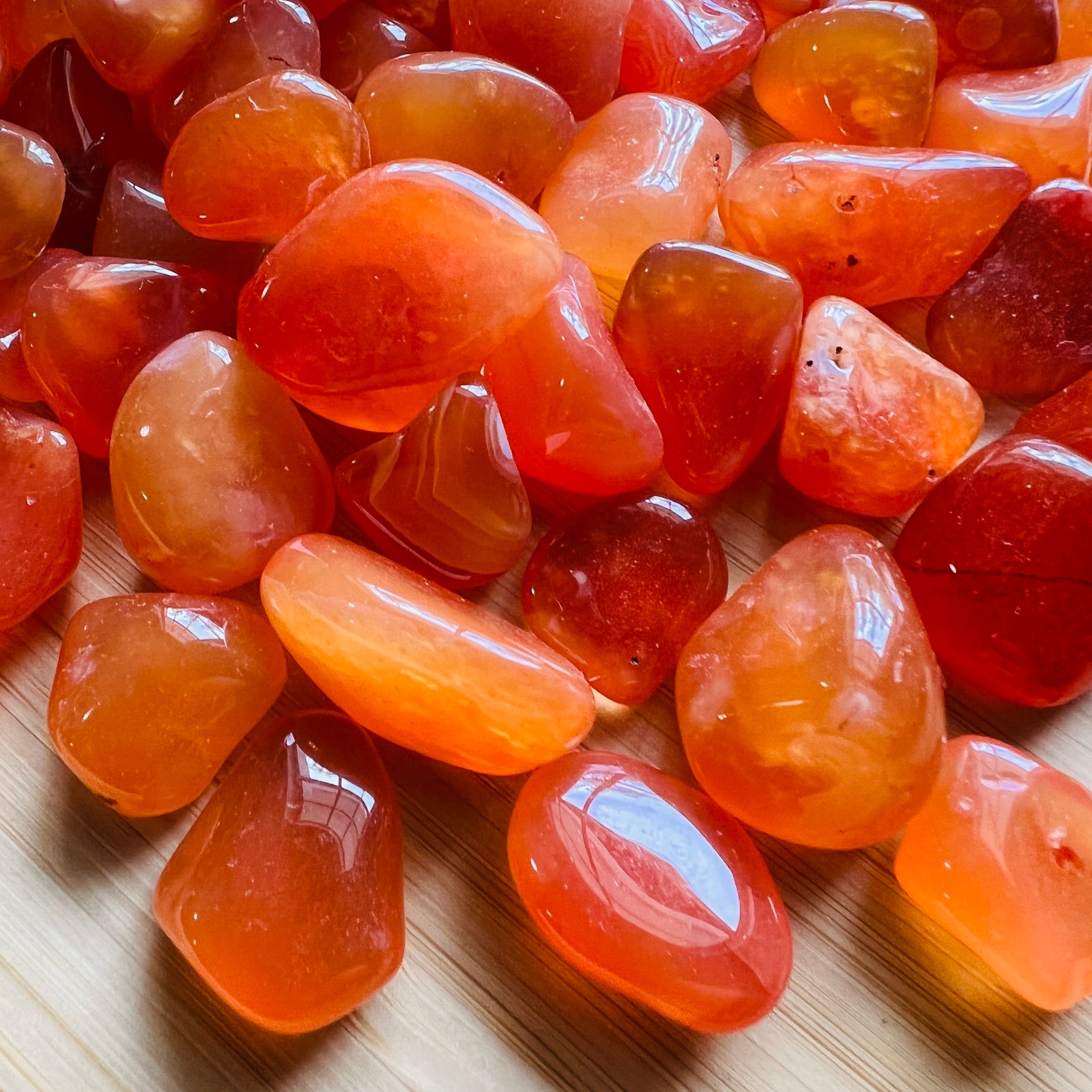 Overhead angle of Grade AA Carnelian tumbled stone, showing characteristic color, associated with Energy.