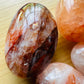 Near view of red Fire Quartz palm stone, showing soft luster.