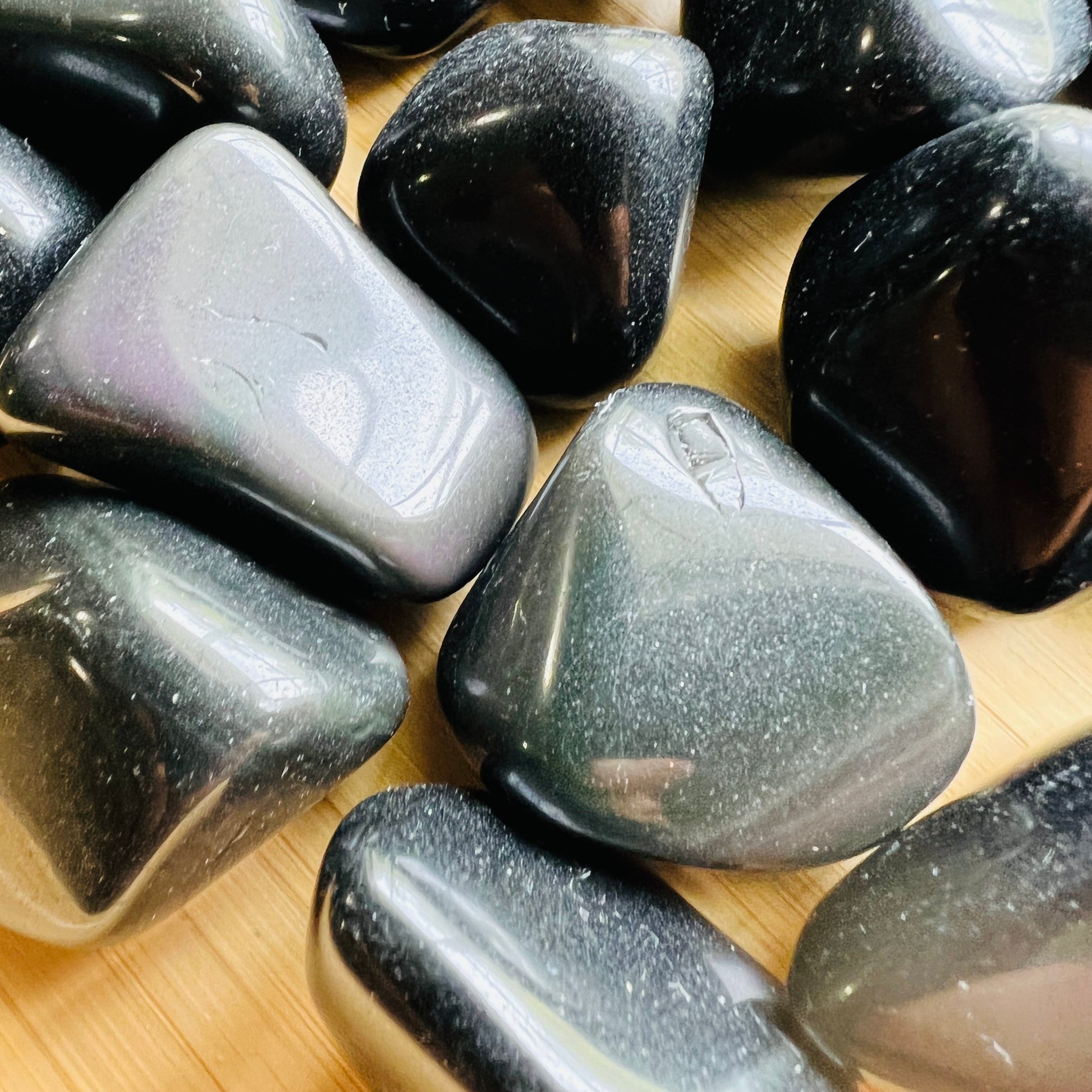 Side-on view of Rainbow Obsidian tumbled stone, showing matte finish, hand-selected from Jalisco, Mexico.
