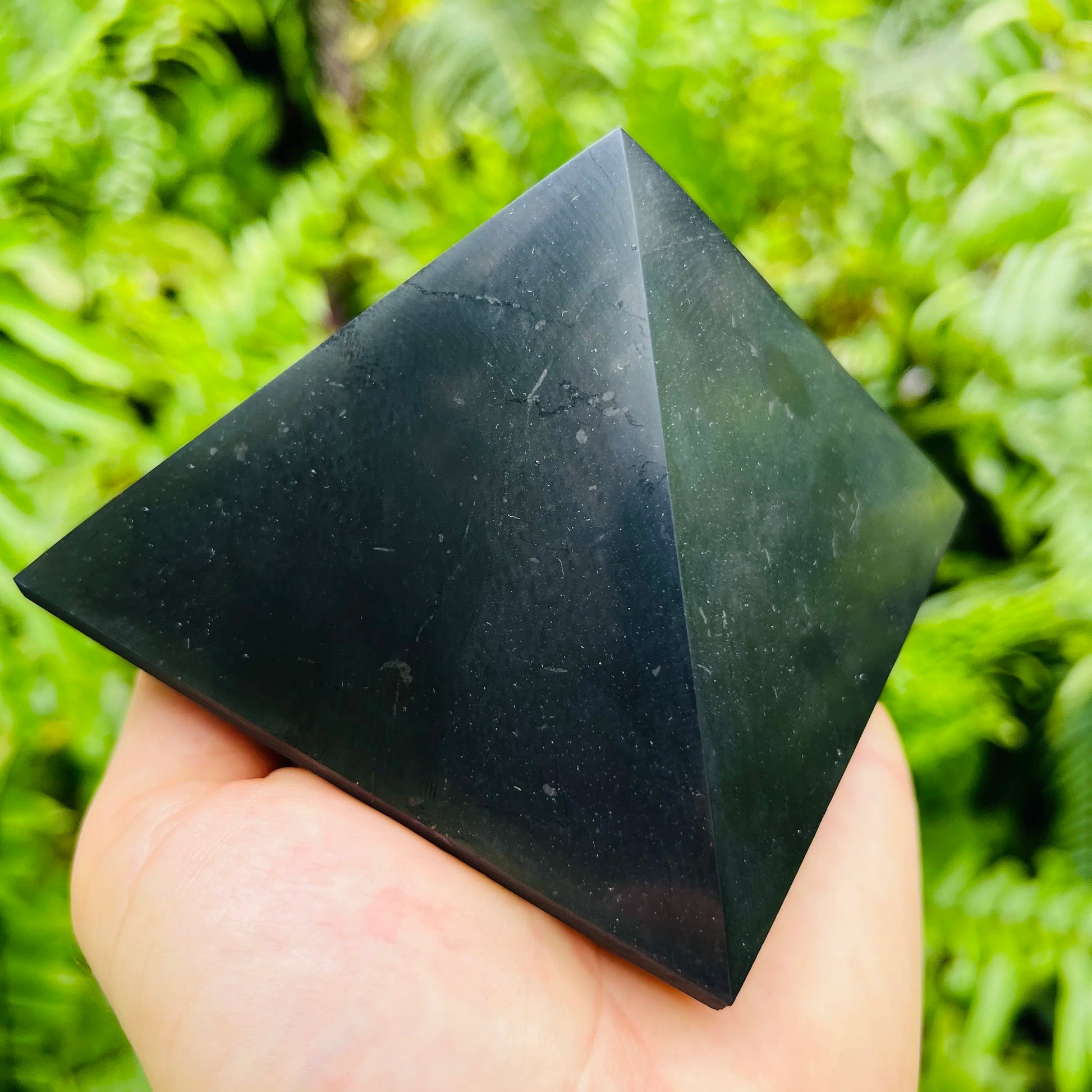 Daylight view of a Shungite polished pyramid associated with Protection and Cleansing.