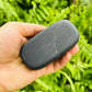 Grain detail of Shungite palm stone, often worked with for Protection, showing translucent edges.