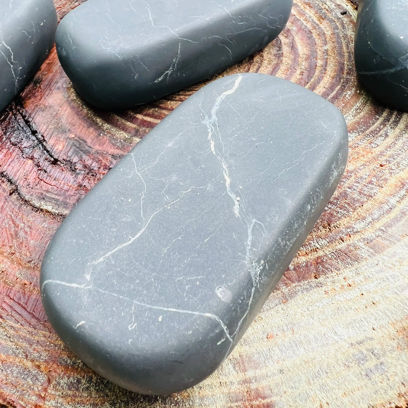 Reverse angle of black Shungite palm stone, showing earthy tone, worked with for Protection.