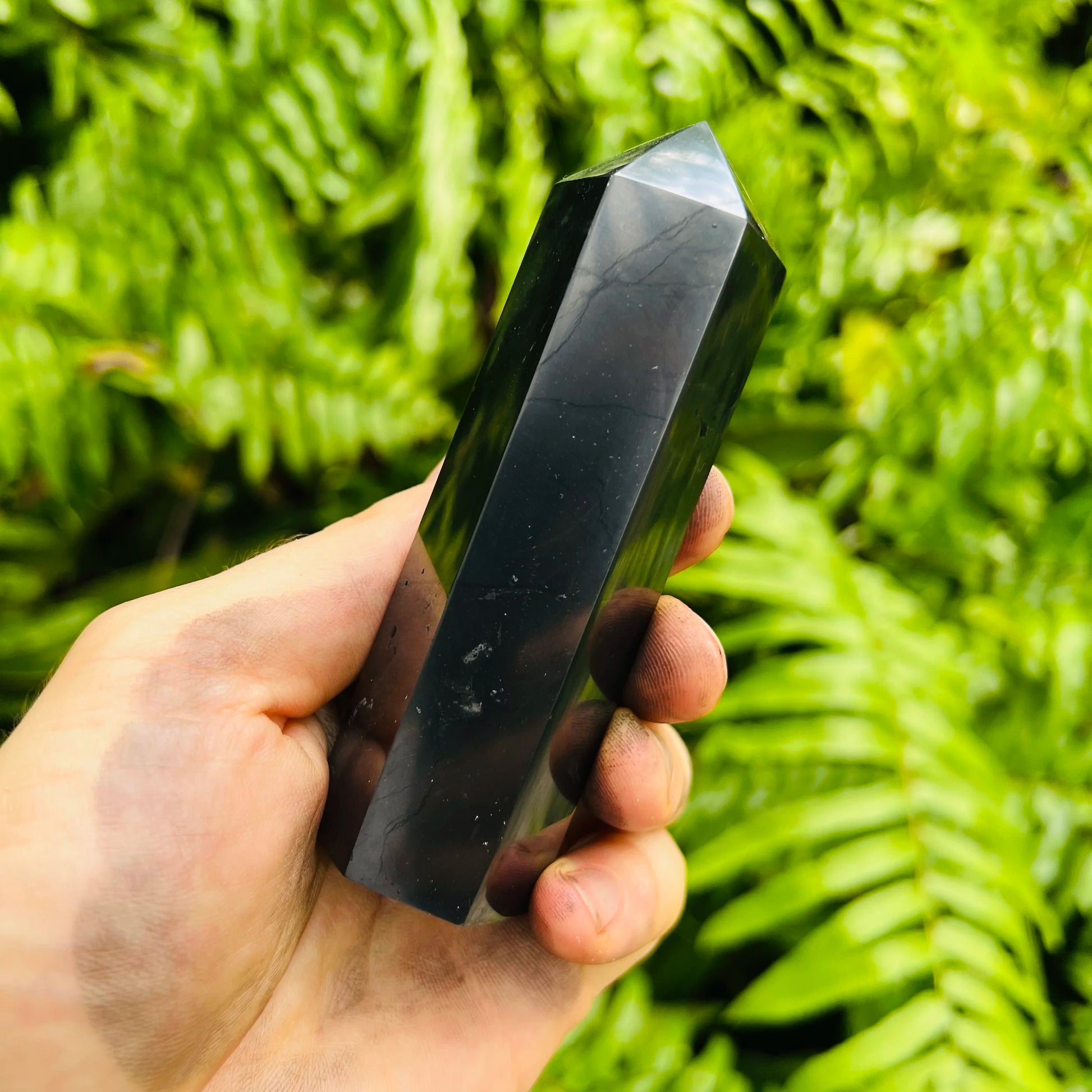 Near view of Shungite polished point, sourced from Republic of Karélia, Russia, showing glassy finish.