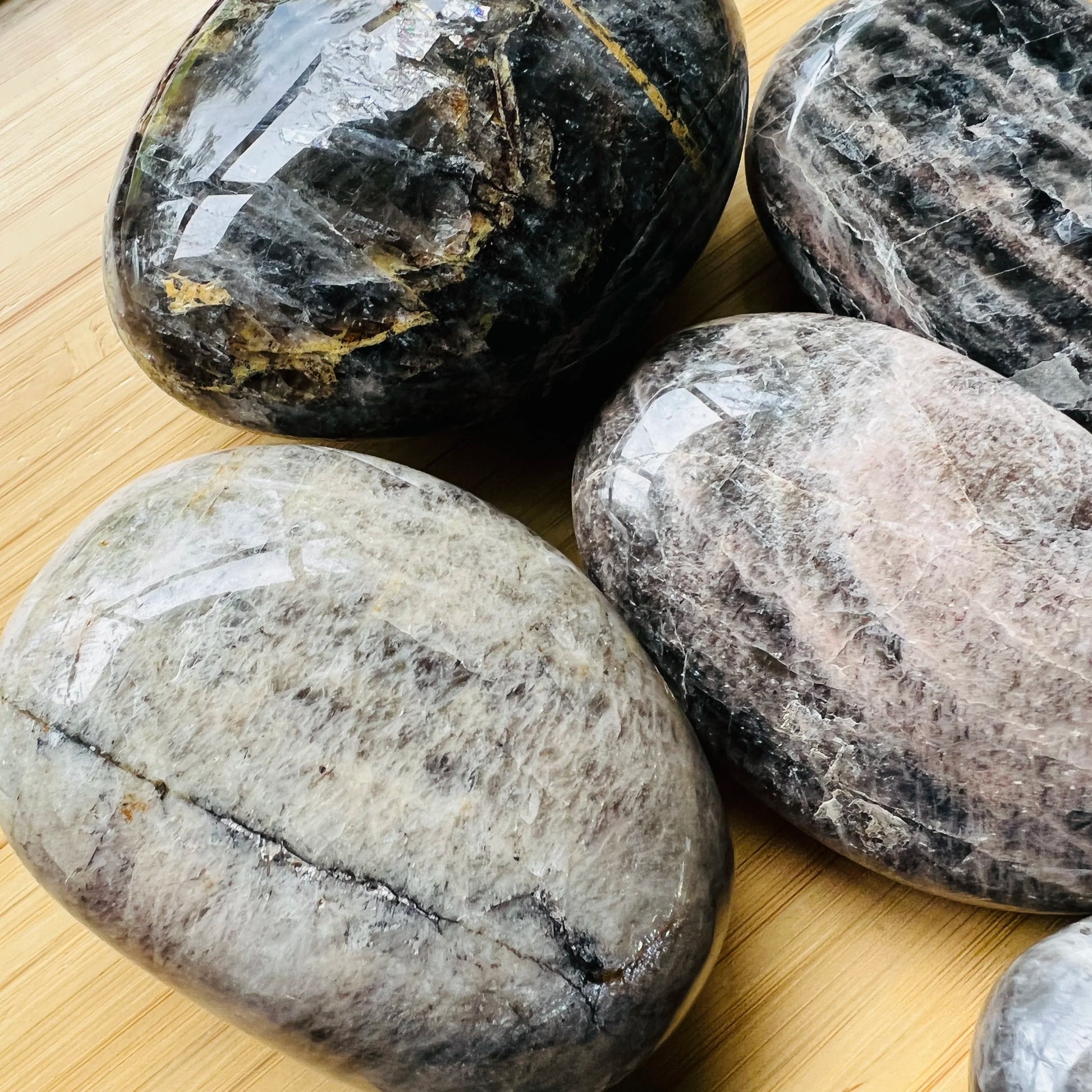 Side-on view of Black Moonstone palm stone, Madagascar-sourced, showing natural inclusions.