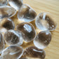 Palm-scale view of one Clear Quartz tumbled stone for scale, hand-selected from Minas Gerais, Brazil.