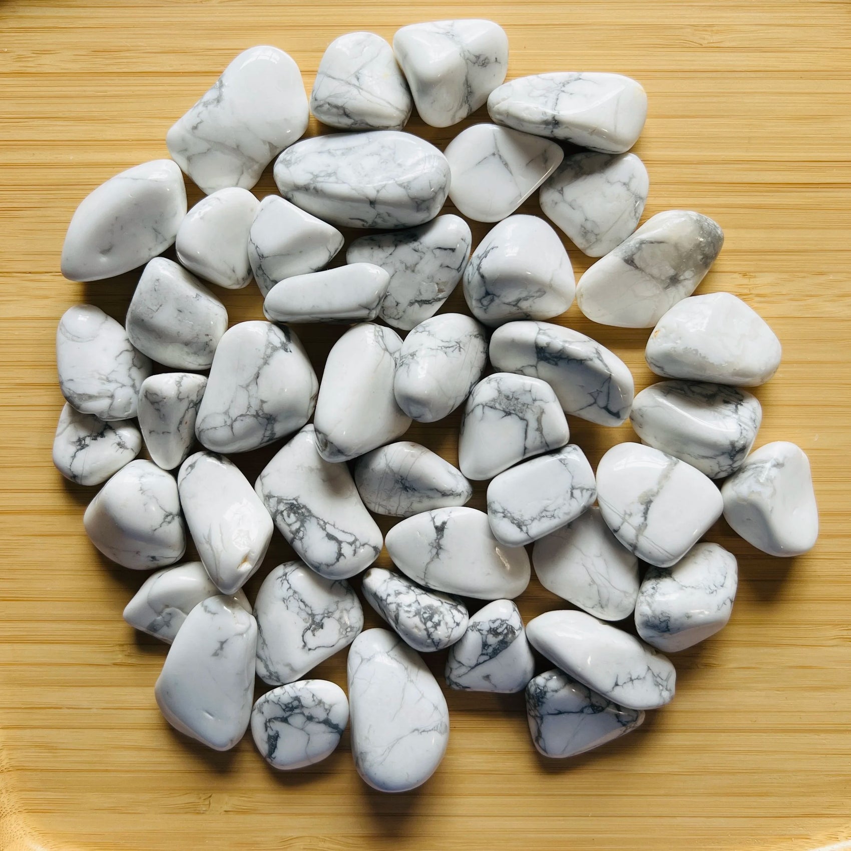 Lifestyle still of Howlite tumbled stone, shown at hand scale.