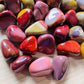 Held in hand, a Mookaite tumbled stone carried for Grounding.