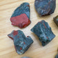 Hand-scale shot of one Bloodstone raw stone for scale, sourced from Eswatini.