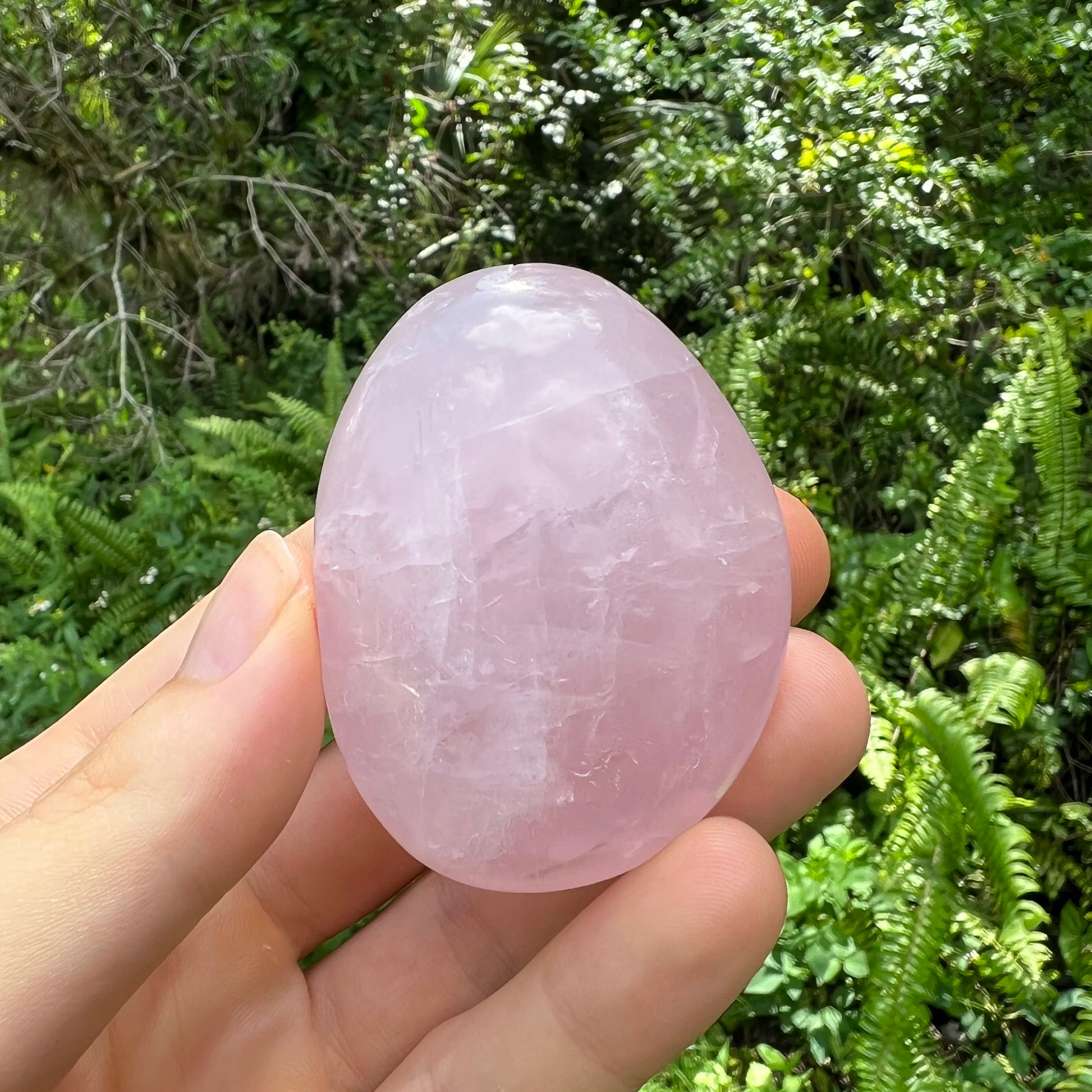 Profile view of pink Rose Quartz palm stone, showing earthy tone, turned to for Love.