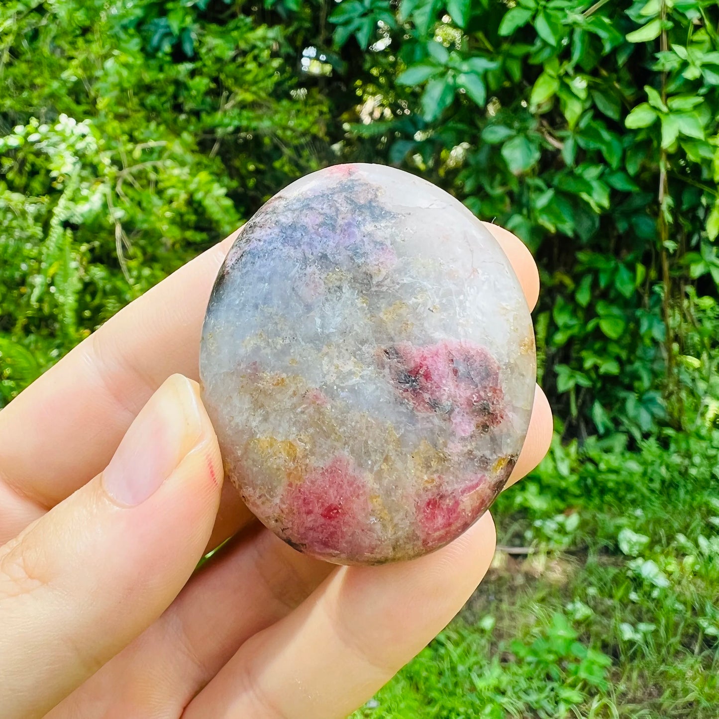 Side profile of pink Rhodonite palm stone, Madagascar-sourced, showing matte finish.