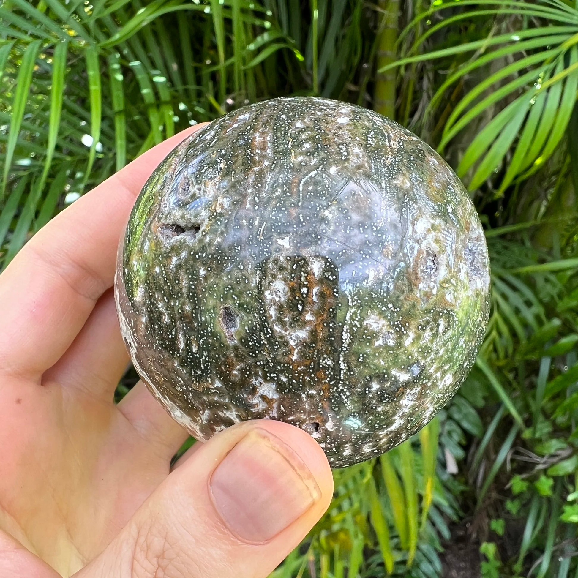 Held in hand is an Ocean Jasper stone, in the warmth of daylight.