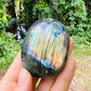 Side-on view of Labradorite palm stone, showing natural inclusions.