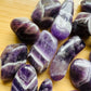 Lateral view of Grade AA Chevron Amethyst tumbled stone, showing characteristic patterning.