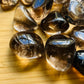 Close detail of Smoky Quartz tumbled stone, kept close for Grounding and Protection, sourced from Brazil.