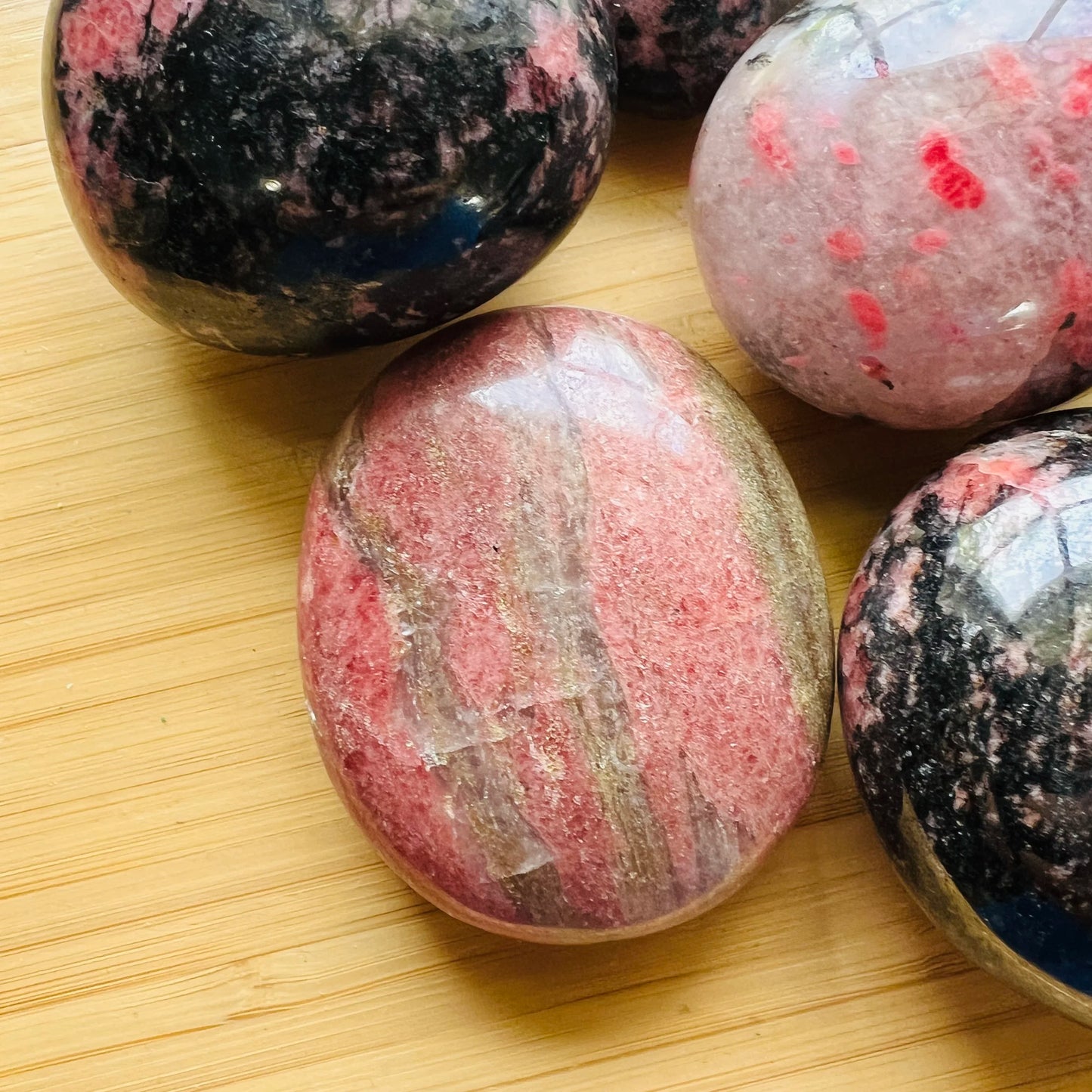 Back view of Grade AA Rhodonite palm stone showing natural surface