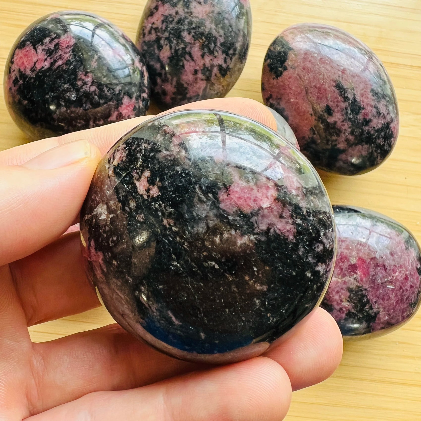 Daylight view of a Rhodonite palm stone worked with for Emotional Healing, from Madagascar.