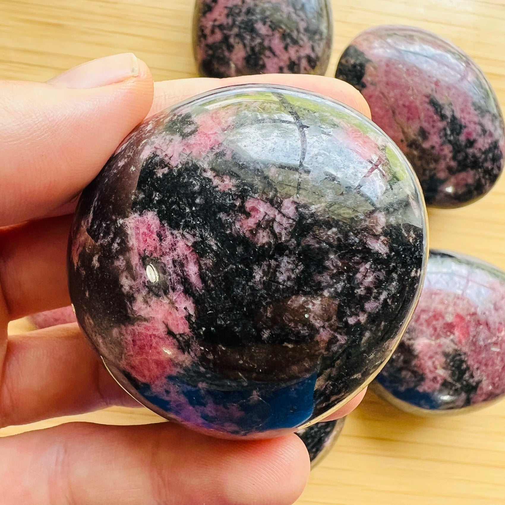 Reverse angle of Rhodonite palm stone, from Madagascar, showing translucent edges.