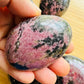 Detail shot of Grade AA Rhodonite palm stone under natural light
