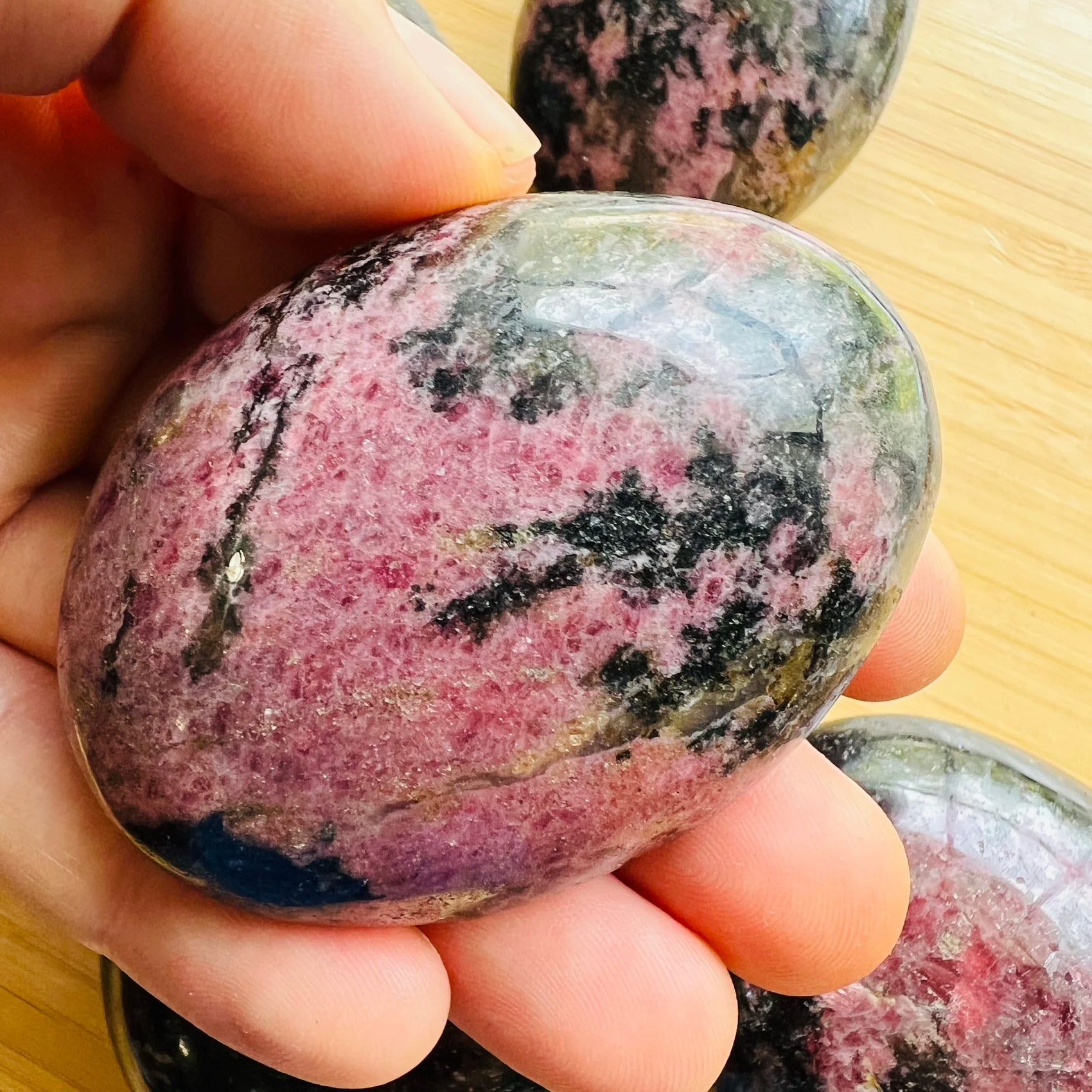 Detail shot of Grade AA Rhodonite palm stone under natural light
