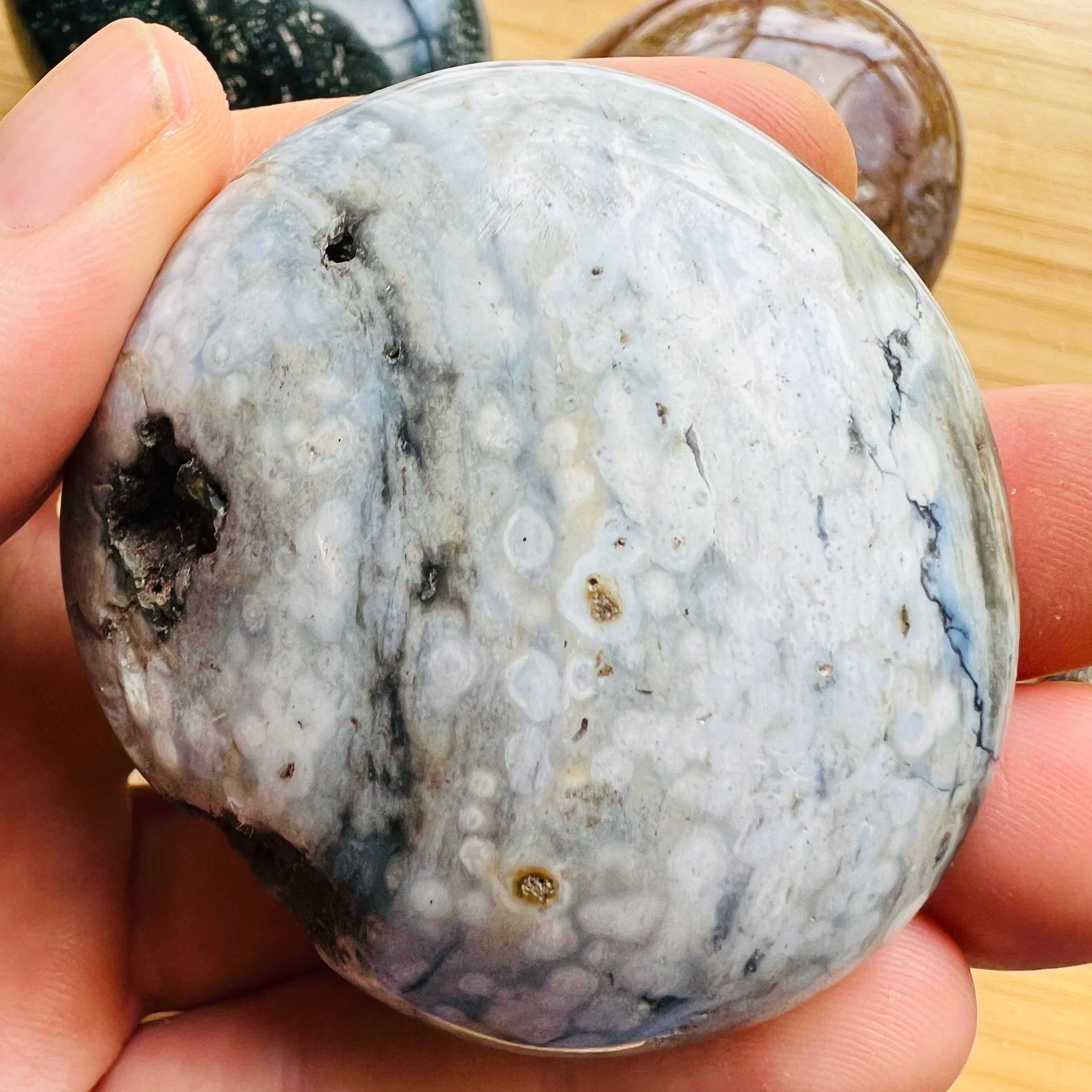Detail shot of Grade AA Ocean Jasper palm stone under natural light